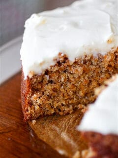 carrot cake with creamy cream cheese frosting cut with one slice missing