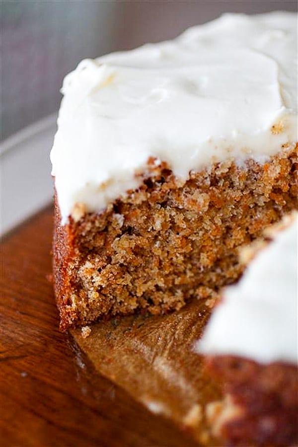 carrot cake with creamy cream cheese frosting cut with one slice missing