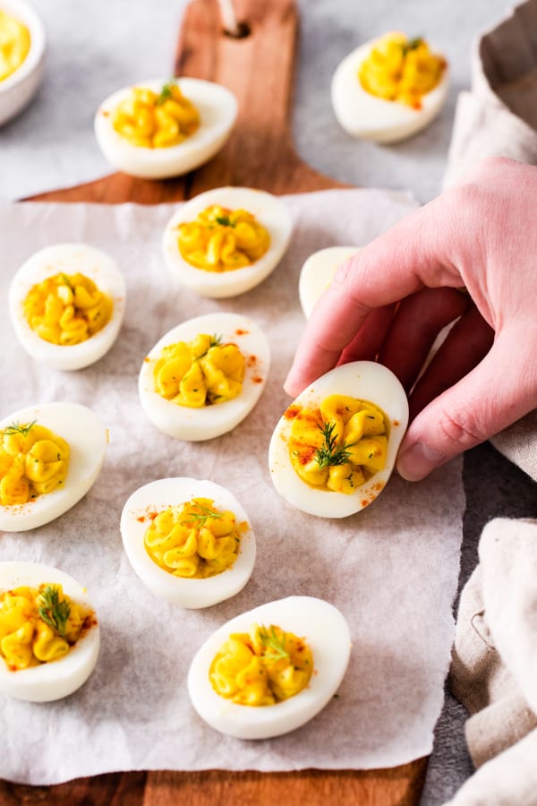 A hand picking up a deviled egg. 