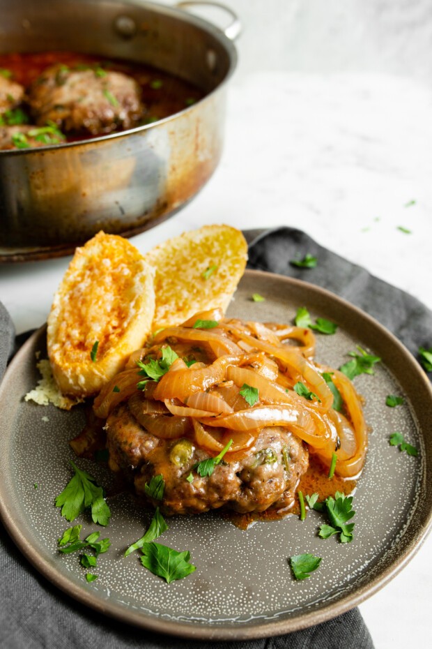 French Onion Salisbury Steak on a plate topped with onions. 