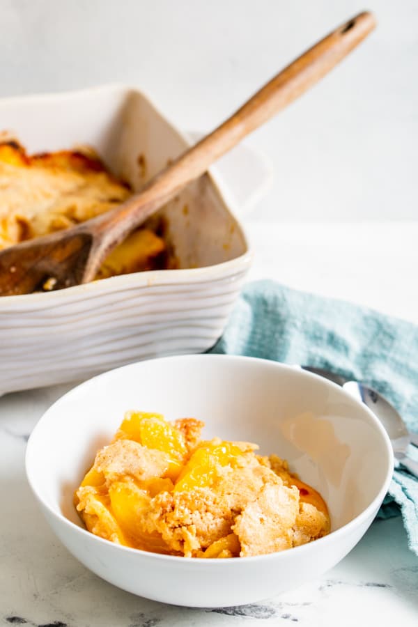 frozen peach cobbler scooped out into a bowl