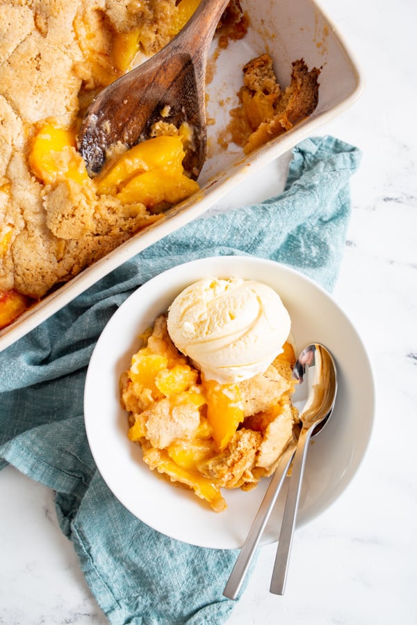 a bowl full of frozen peach cobbler with ice cream