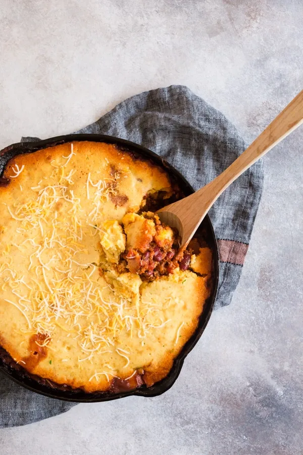 Buttermilk Cornbread Topped Chili being spooned out of the skillet. 