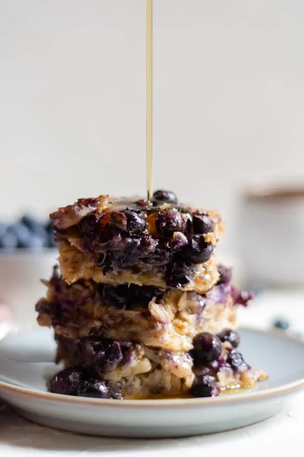 baked blueberry oatmeal on a plate with maple syrup drizzled with maple syrup