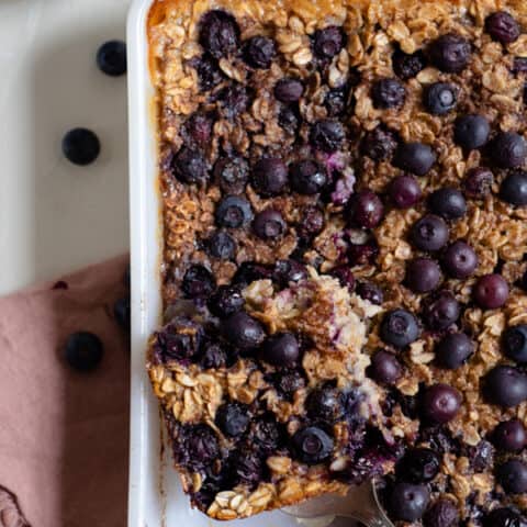 baked blueberry oatmeal in a white dish with a slice cut out