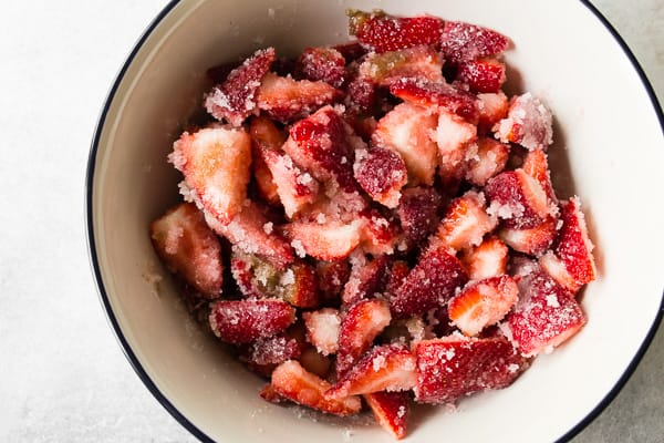 cut strawberries in a large bowl with sugar and vanilla bean paste