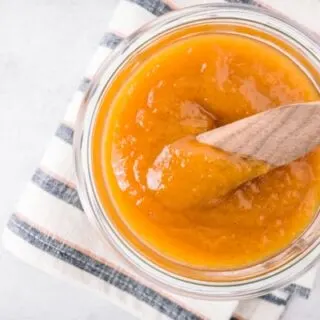 vanilla honey peach butter in a jar with a wooden knife