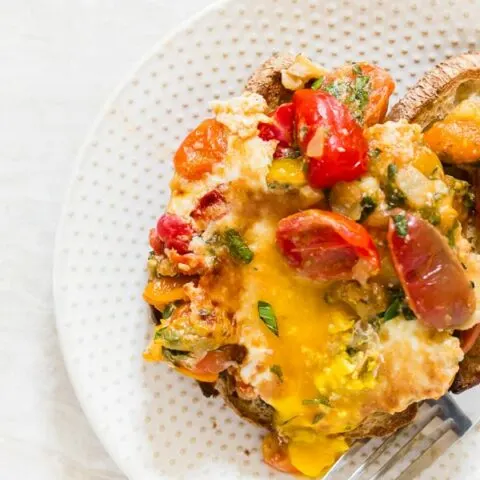 These bruschetta baked eggs are the perfect weekend brunch addition. Sweet sauteed tomatoes mixed with lots of garlic, basil, and oregano and topped with eggs and Parmesan cheese. Serve it over toast and enjoy your weekend! 