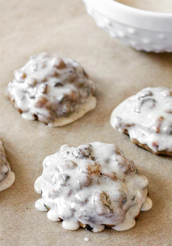 fruit cake cookies with icing sitting on parchment paper