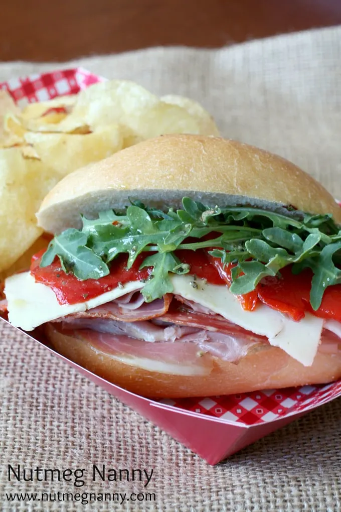Closeup of Italian sub sandwich with potato chips on the side.