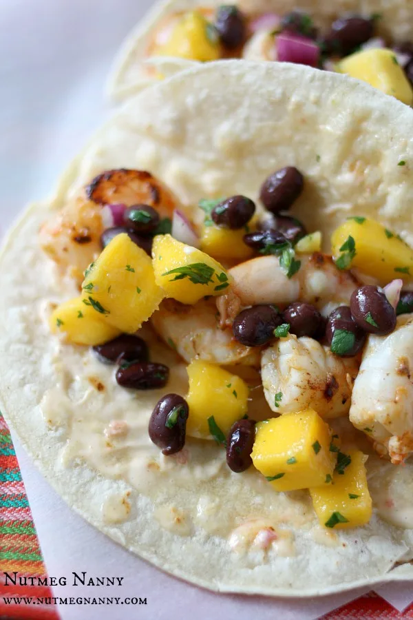 These marinated shrimp tacos with chili mustard aioli are the perfect summertime taco. Packed full of flavor and covered with a sweet mango black bean salsa.