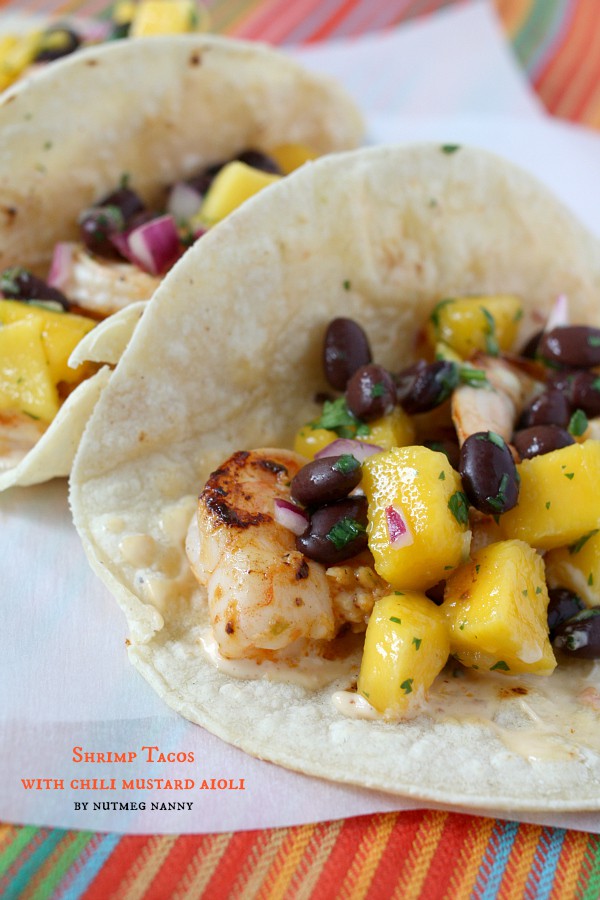 These marinated shrimp tacos with chili mustard aioli are the perfect summertime taco. Packed full of flavor and covered with a sweet mango black bean salsa.