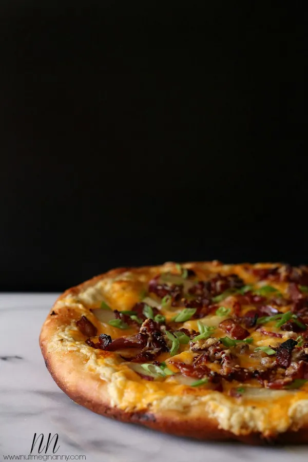 loaded baked potato pizza sitting on a marble cutting board