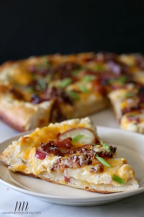 loaded baked potato pizza cut into slices on a plate