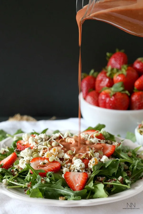 Strawberry dressing being poured onto a salad. 