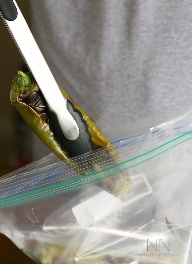 putting a roasted hatch green chile into a ziplock bag.
