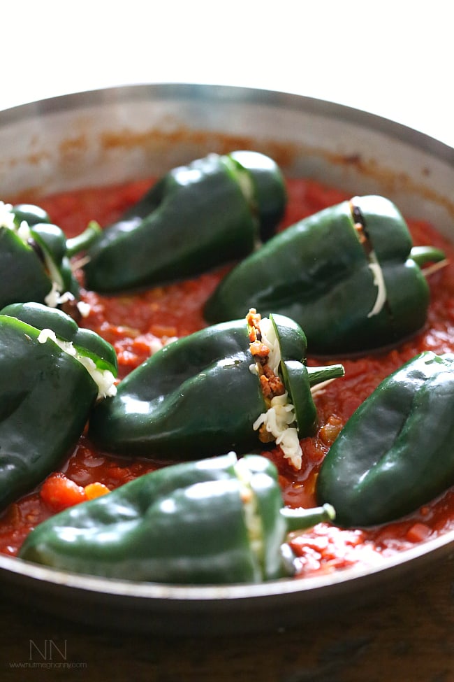 These chorizo stuffed poblano peppers are packed full of spicy chorizo, black beans, sweet corn, oaxaca cheese and baked in a flavorful tomato sauce. If you're looking for a new version of stuffed peppers this is the perfect version! Chorizo Stuffed Poblano Peppers in a pan getting ready to be baked.