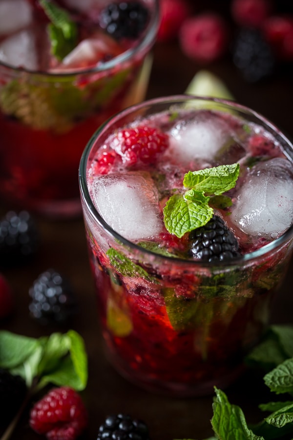 mixed berry mojito in a glass with fresh berries and mint on top. 