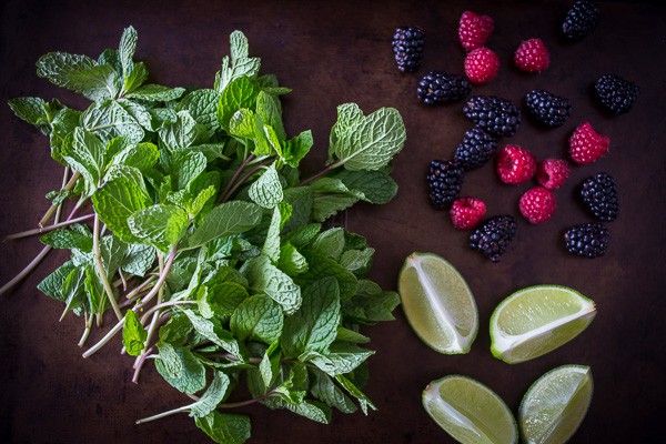 fresh mint, lime, and berries on a plate for mixed berry mojitos. 