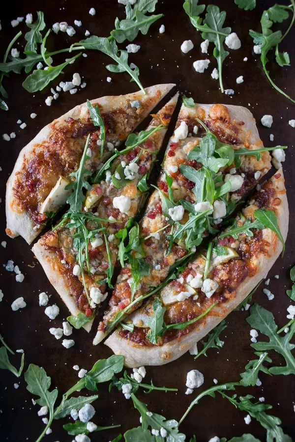 Homemade pizza cut into slices and topped with arugula and blue cheese.