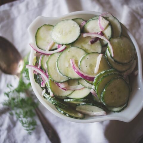 greek yogurt ranch cucumber salad in a white bowl with red onion