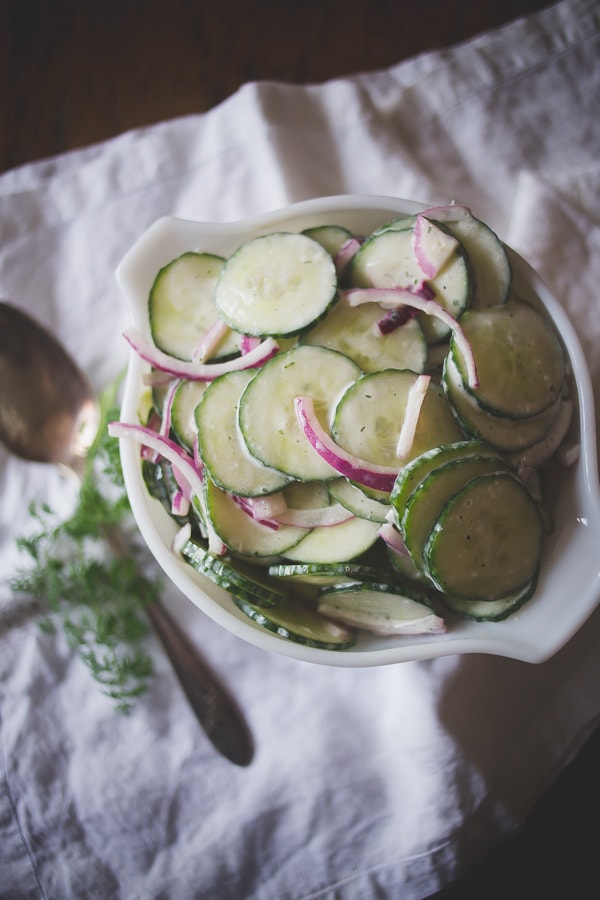 greek yogurt ranch cucumber salad in a white bowl with red onion