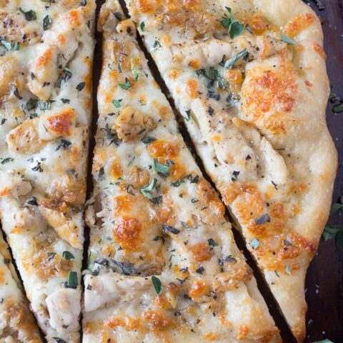 roasted garlic chicken pizza sliced on a sheet pan