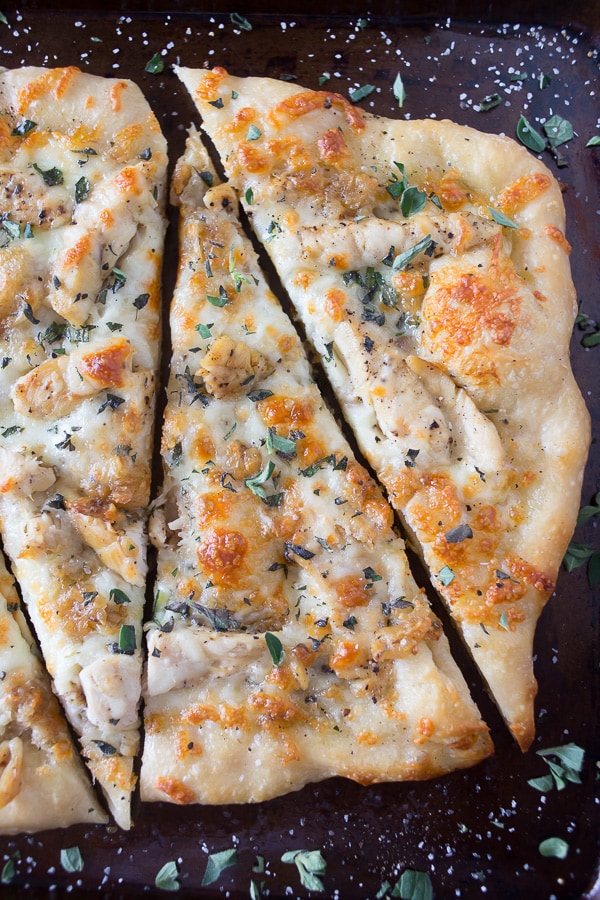 roasted garlic chicken pizza sliced on a sheet pan