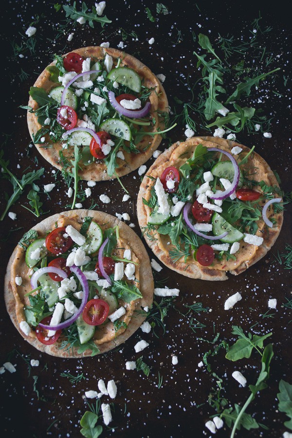 These greek salad hummus pita pizzas are the perfect summertime appetizer or main course meal. Olive oil grilled pita topped with spicy hummus and fresh Greek salad. You're going to love this!