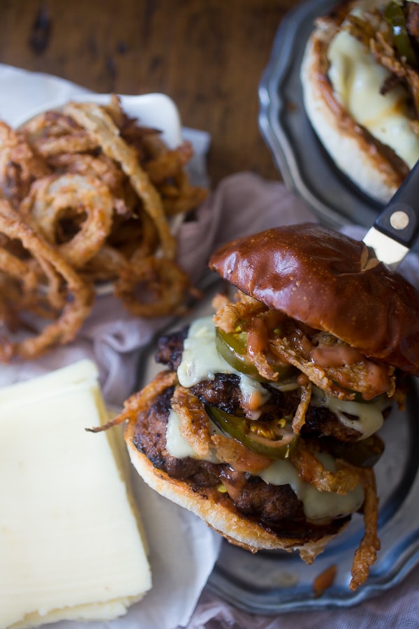 This chorizo beef burger with crispy onion straws is the perfect big mouth burger. Topped with bbq fry sauce, candied jalapeños and American cheese. 