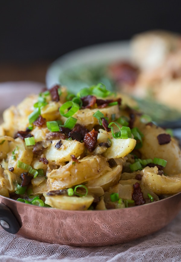 This warm bacon herb potato salad is the perfect winter side dish. It's the perfect balance of tangy and sweet and ready in just about 30 minutes. Made with soft potatoes, bacon, sautéed onions, garlic, fresh herbs and tossed in a tangy apple cider vinaigrette dressing. 