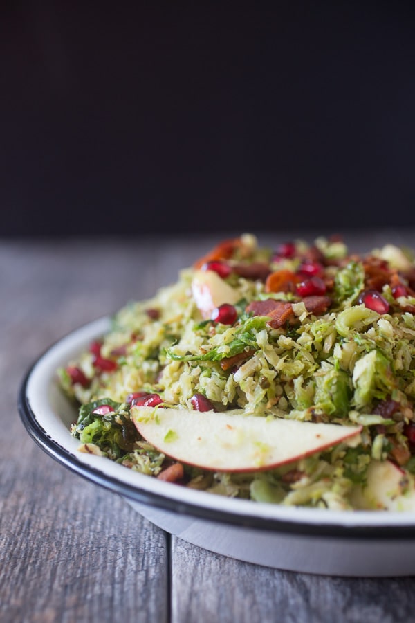 This shaved Brussels sprout apple bacon salad is the perfect combo of sweet, salty and savory. Roasted and shaved Brussels sprouts combined with bacon, candied pecans, sliced apples and pomegranates seeds all drizzled with a simple maple vinaigrette.