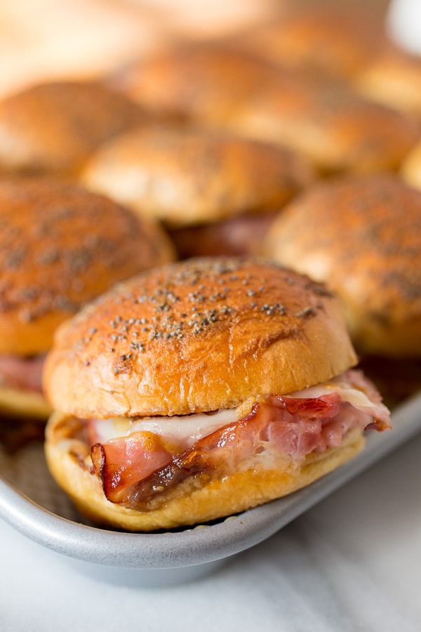 Close up of ham and cheese party sandwiches on a baking tray.