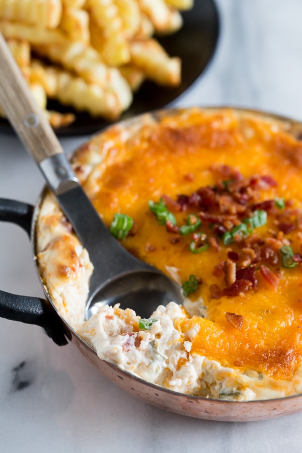 warm loaded baked potato dip in a small dish with a serving spoon. 