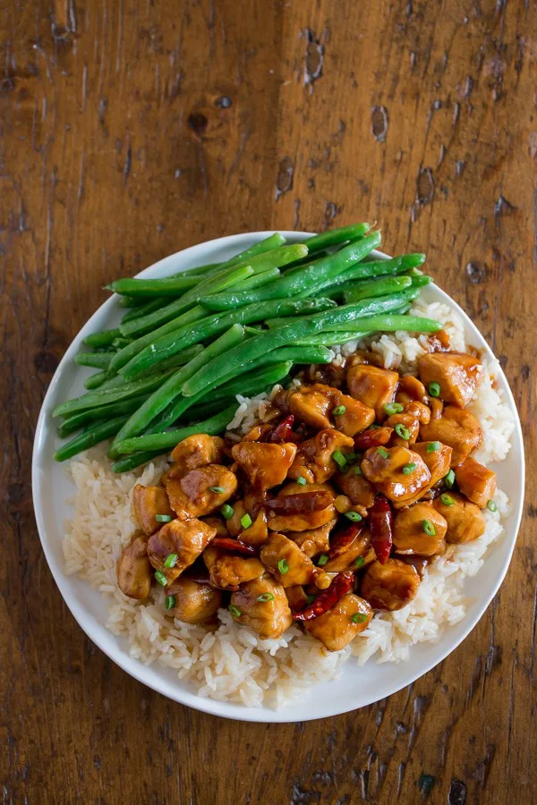 Healthier General Tso's Chicken on a plate with rice and vegetables. 