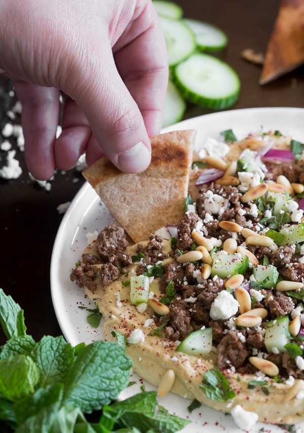 This Greek topped hummus is packed full of flavor. Topped with spiced lamb, cucumber, red onion, pine nuts, feta cheese, mint and a sprinkling of sumac. Serve with pita chips and DIG IN! 