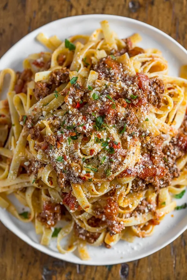 Slow Cooker Parmesan Meat Sauce on a plate spooned over pasta. 