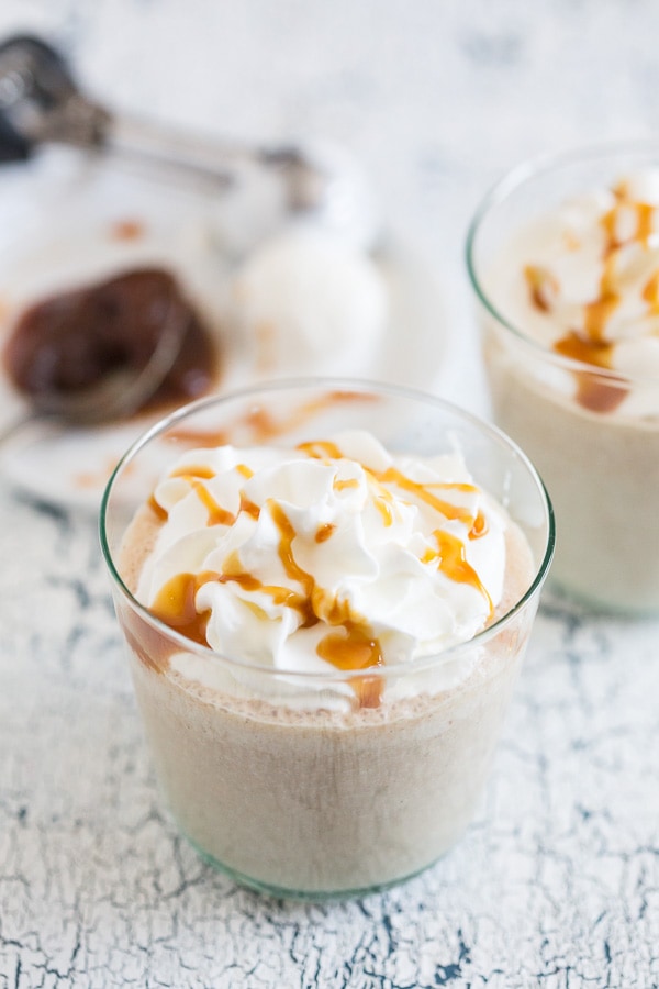 boozy caramel apple butter milkshake in a small glass with caramel and whipped cream