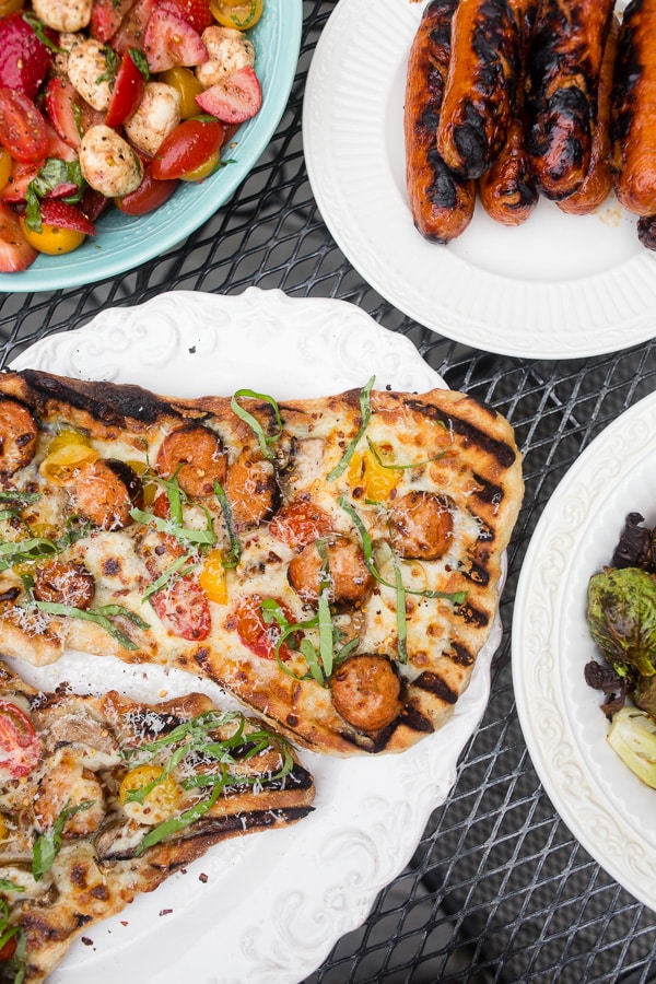 This grilled chicken sausage pizza is made 100% on the grill and is perfect for jazzing up your normal bbq routine. Topped with grilled chicken sausage, mushrooms, cherry tomatoes, mozzarella cheese and lots of fresh basil. You'll want to make this part of your summer as soon as possible!