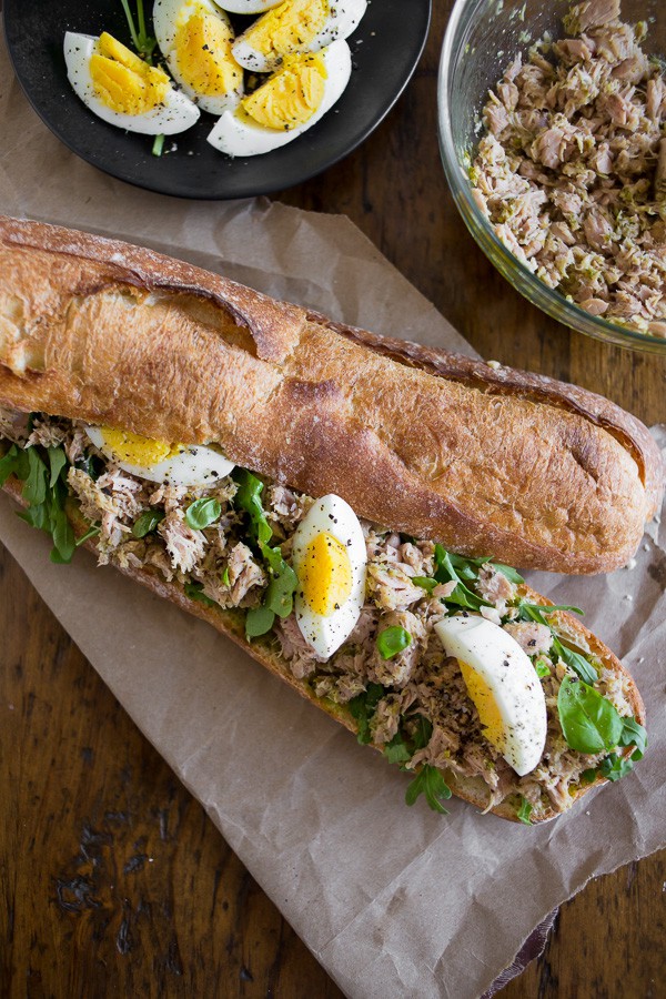 This pesto tuna baguette sandwich is the perfect summer sandwich. Fresh basil pesto mixed with olive oil canned yellowfin tuna and piled high on a baguette with arugula and hard boiled eggs. You'll love this sandwich! 