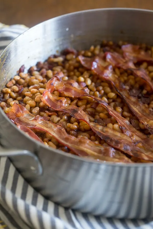Molasses Bacon Baked Beans in a skillet topped with bacon. 