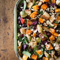 This fall panzanella salad is packed full of fresh roasted vegetables, dried cranberries, pine nuts, feta cheese, buttery toasted gluten free bread and drizzled with a maple syrup herb vinaigrette. This salad is 100% fall and perfect for the holidays!