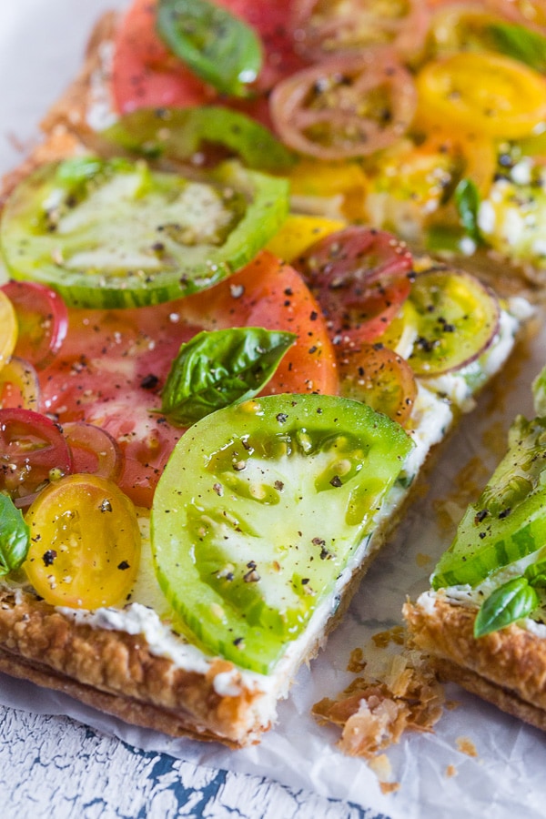 This super simple heirloom tomato tart is made with puff pastry, lemon and fresh herb ricotta and covered with lots of freshly sliced heirloom tomatoes. Ready in just 25 minutes and perfect for an appetizer or a light dinner.