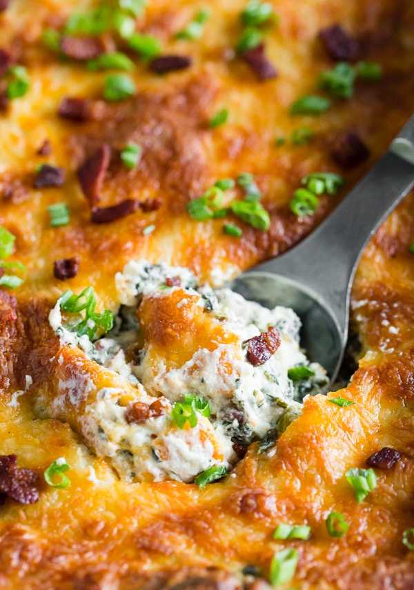 This baked spinach bacon dip is the perfect party snack. Packed full of spinach, crispy bacon, cream cheese, sharp cheddar cheese and green onions. This dip is so easy you'll want to make it every single weekend! PLUS it's ready in just 30 minutes!