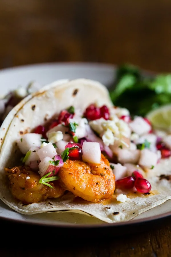 These shrimp tacos with apple pomegranate salsa are the perfect balance of sweet and heat. The shrimp are sauteed in cajun seasoning and topped with a delicious salsa made from apples, pomegranates, red onion, cilantro and lime. You'll love these super easy and crazy delicious tacos.