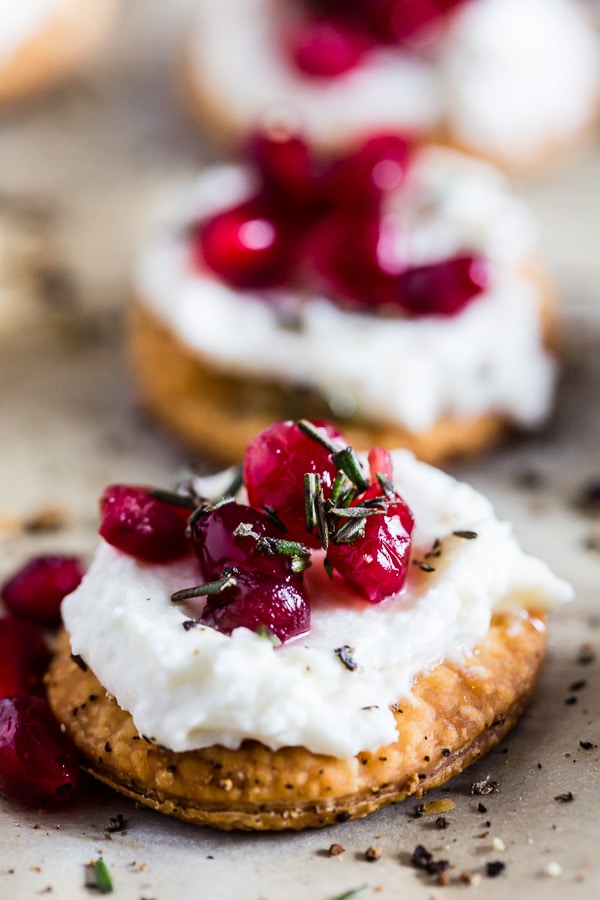 These beautiful whipped goat cheese pomegranate bites are made in less than 30 minutes and are the perfect stunning holiday appetizer. Store bought pie crust is cut out and baked into little flakey cracker rounds and topped with honeyed whipped goat cheese, pomegranate seeds and a sprinkling of honey and rosemary. You will love this new quick and easy holiday appetizer! 