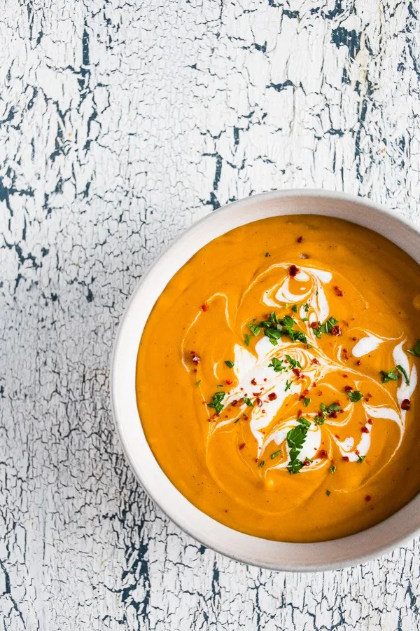 creamy red lentil carrot soup in a bowl topped with cilantro