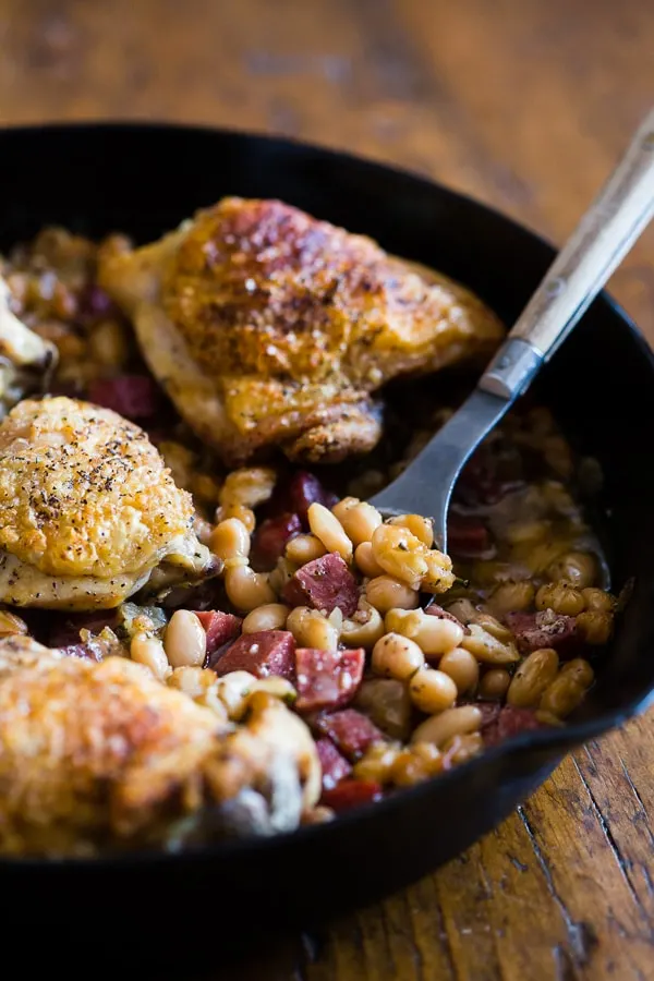 This chicken cannellini bean skillet is the perfect cozy winter meal you crave. Delicious white beans cooked with cubed sausage, onions and rosemary and topped with super crispy chicken thighs. This dish is hearty, delicious and full of flavor!