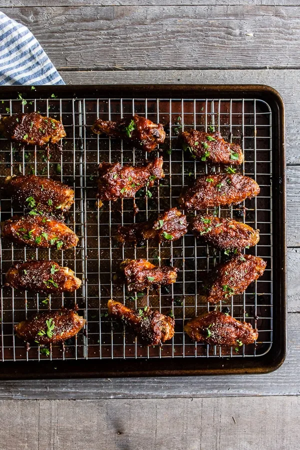 Apple butter chicken wings on a baking tray and grilling rack.