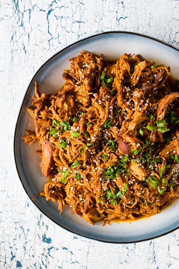 This slow cooker honey soy sriracha pulled chicken is packed full of flavor and made all in the slow cooker. All you need are a few easy ingredients, a slow cooker and 4-6 hours. Serve it over rice, on a bun or straight from the slow cooker!